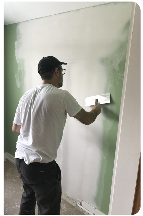 Drywall contractor smoothing joint compound on interior wall during professional drywall patch repair.